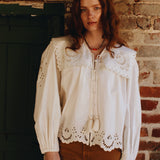 Full view of white button up shirt with scalloped edges, tie neck, and statement balloon sleeves.
