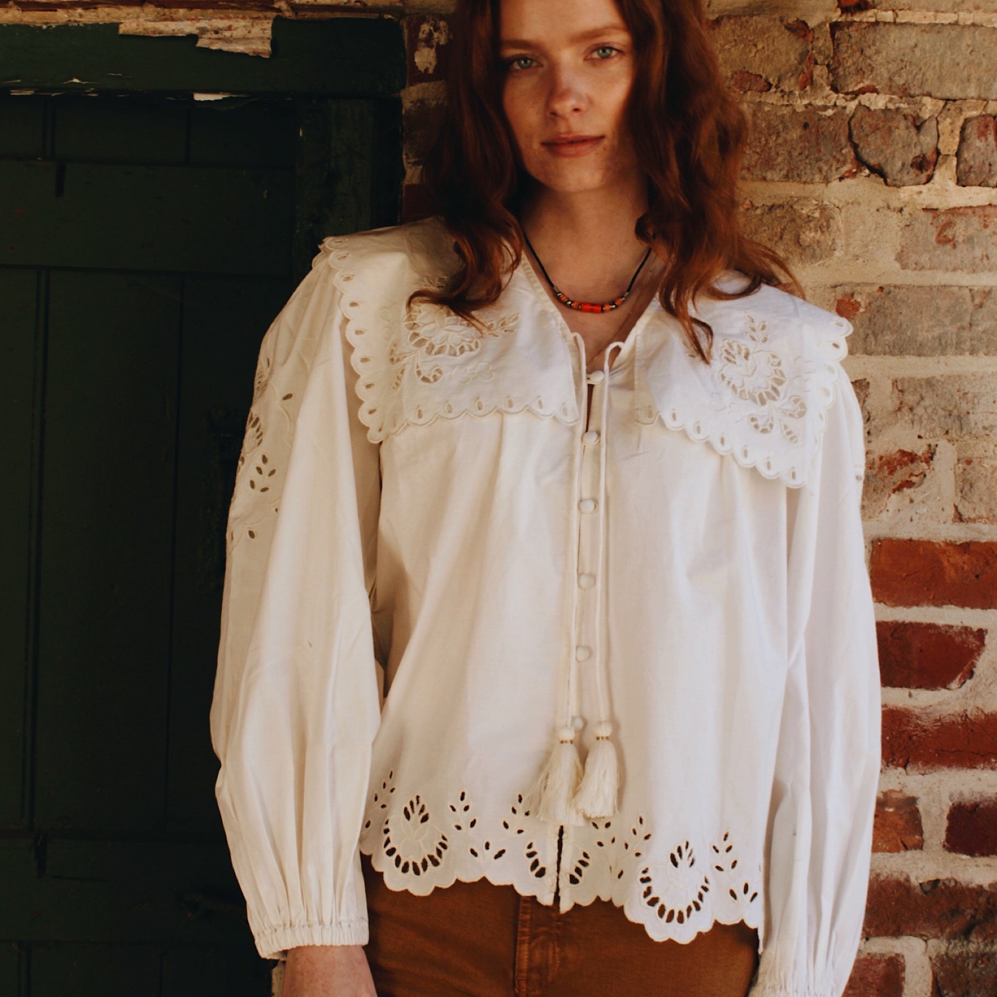 Full view of white button up shirt with scalloped edges, tie neck, and statement balloon sleeves.