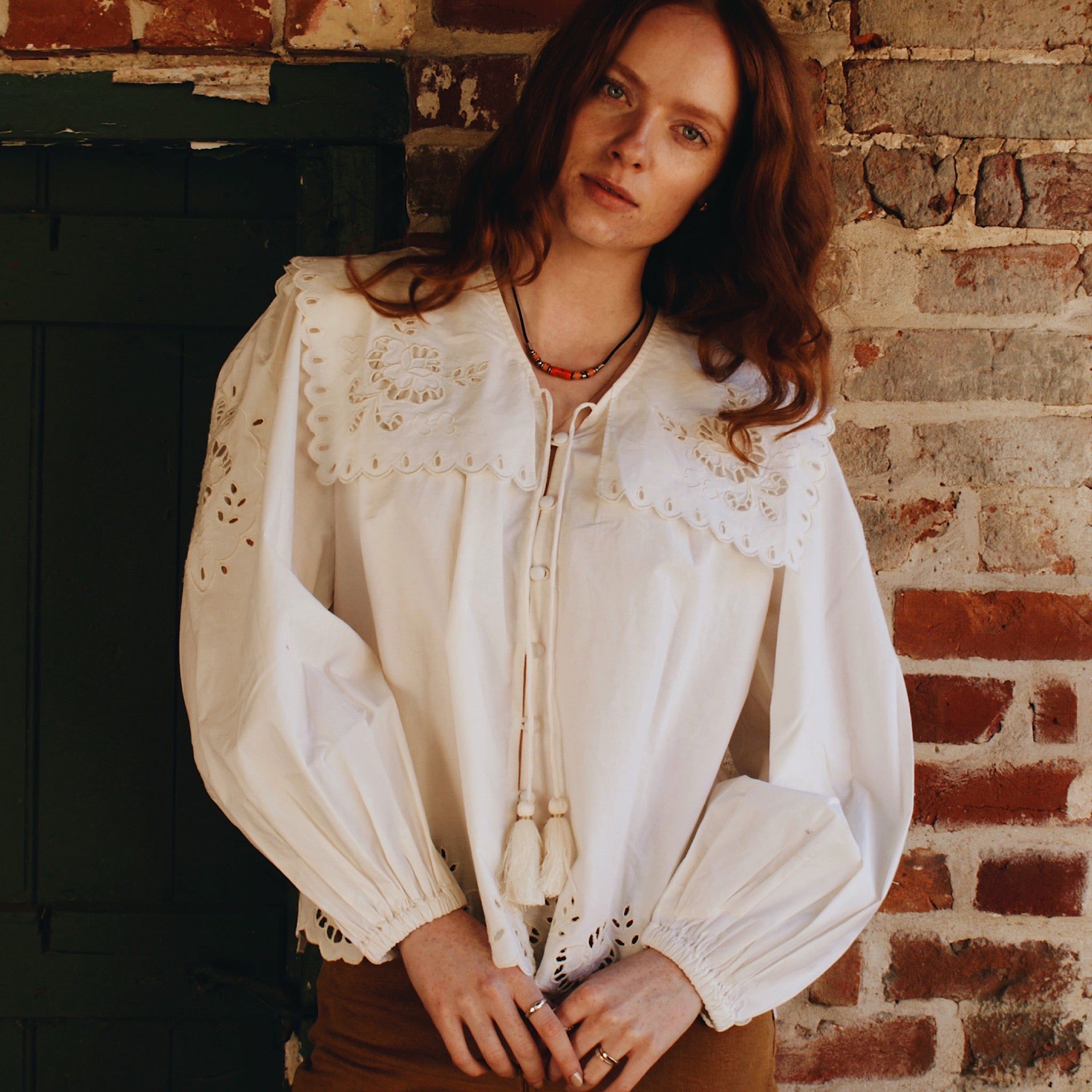 White long sleeve blouse featuring a tie neck and oversized collar with delicate embroidery detail.