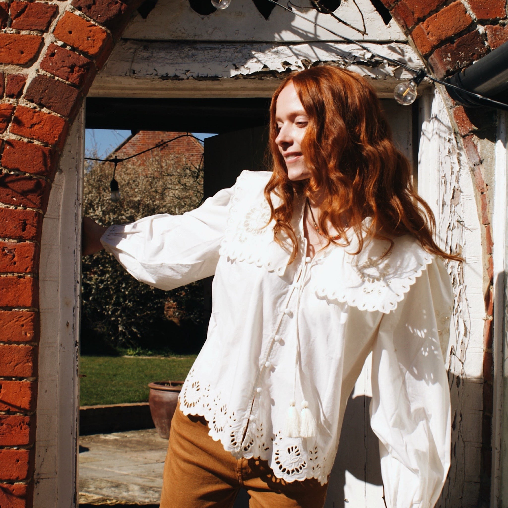 White button up shirt with tie neck and oversized collar, highlighting embroidered front placket.
