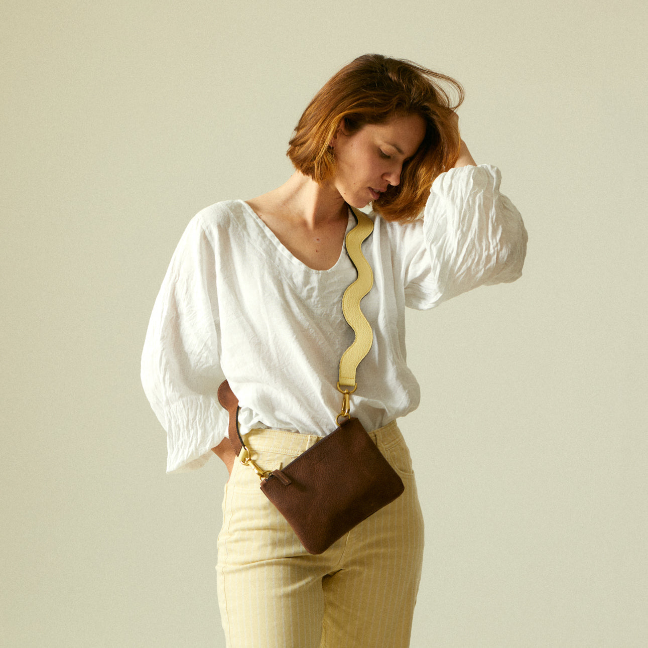 Small yellow leather handbag with shoulder strap on white background.
