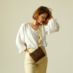 Small yellow leather handbag with shoulder strap on white background.