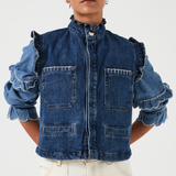 woman wearing a blue denim vest/ waistcoat with our signature white stitch detailing, two large patch pockets, and a frill collar with a blue shirt and white jeans against a white background