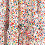 The Felicity Cotton Dress in bright floral Rainbow Meadow print, perfect for everyday wear with a flattering fit and playful ruffle details.