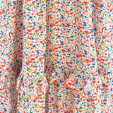 The Felicity Cotton Dress in bright floral Rainbow Meadow print, perfect for everyday wear with a flattering fit and playful ruffle details.
