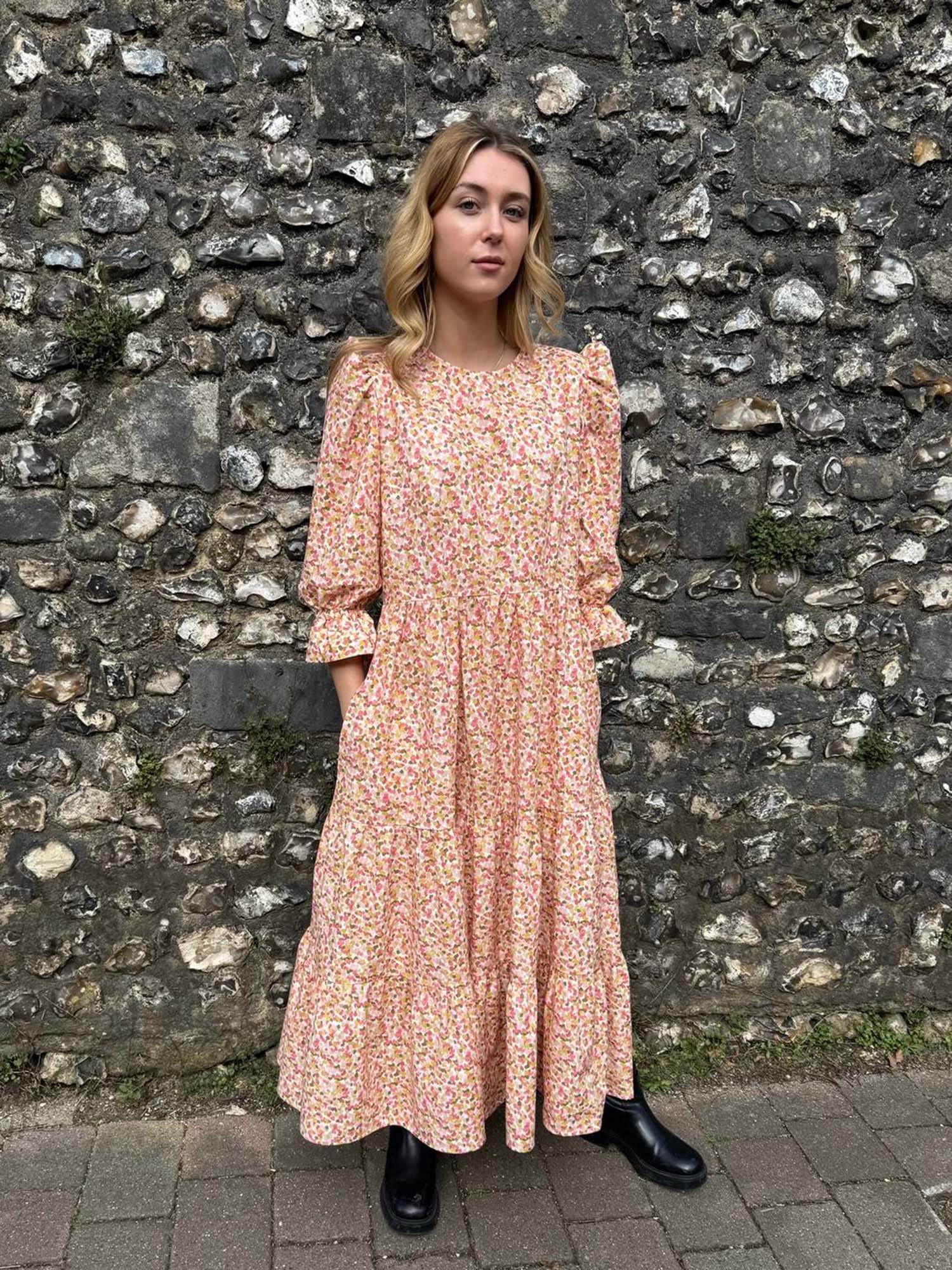 Ethical fashion – Model in The Grace Dress, featuring a tiered skirt, puff sleeves, and frill cuffs, made from sustainable deadstock cotton.