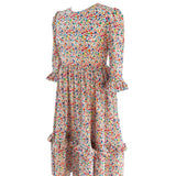 Side view of The Felicity Dress in Rainbow Meadow print, featuring a full skirt, side seam pockets, and gathered 3/4 sleeves with double ruffles.