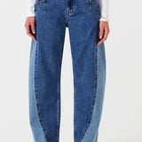 Woman wearing two toned blue barrel leg jeans and a white shirt on a white background