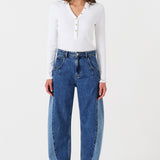 Woman wearing two toned blue barrel leg jeans and a white shirt on a white background