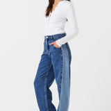 Woman wearing two toned blue barrel leg jeans and a white shirt on a white background phtoographed from the side
