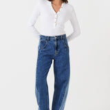 Woman wearing two toned blue barrel leg jeans and a white shirt on a white background