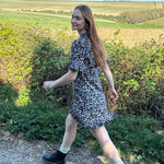 Model walking in UK-made floral mini dress with subtle ruffle detail.