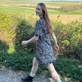 Model walking in UK-made floral mini dress with subtle ruffle detail.