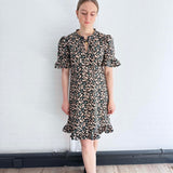 Front view of sustainable floral mini dress with ruffle hem, crafted in the UK.