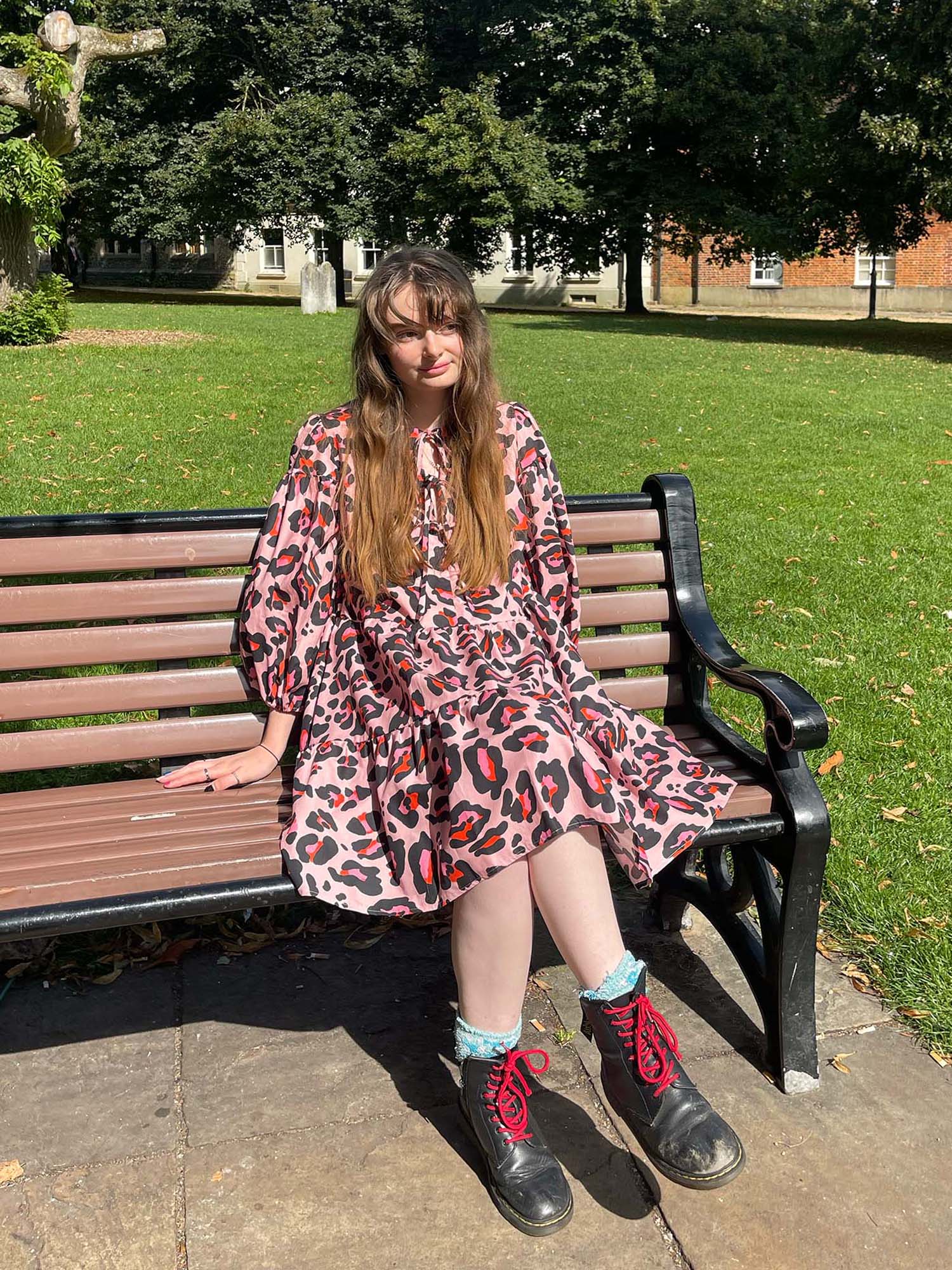 women wearing pink leopard dress sat on bench