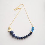 Veering into new waters with the atoll necklace, this piece is made up of blue beads as well as the signature brass, by Percy Langley