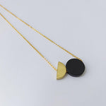 A fun geometric combination made up of a black solid circle and a brass semi circle, this is a necklace beautiful in it's simple shape, by Percy Langley
