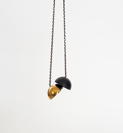 A statement necklace with two solid half-spheres creating a unified ball or two halves on the same chain, by Percy Langley