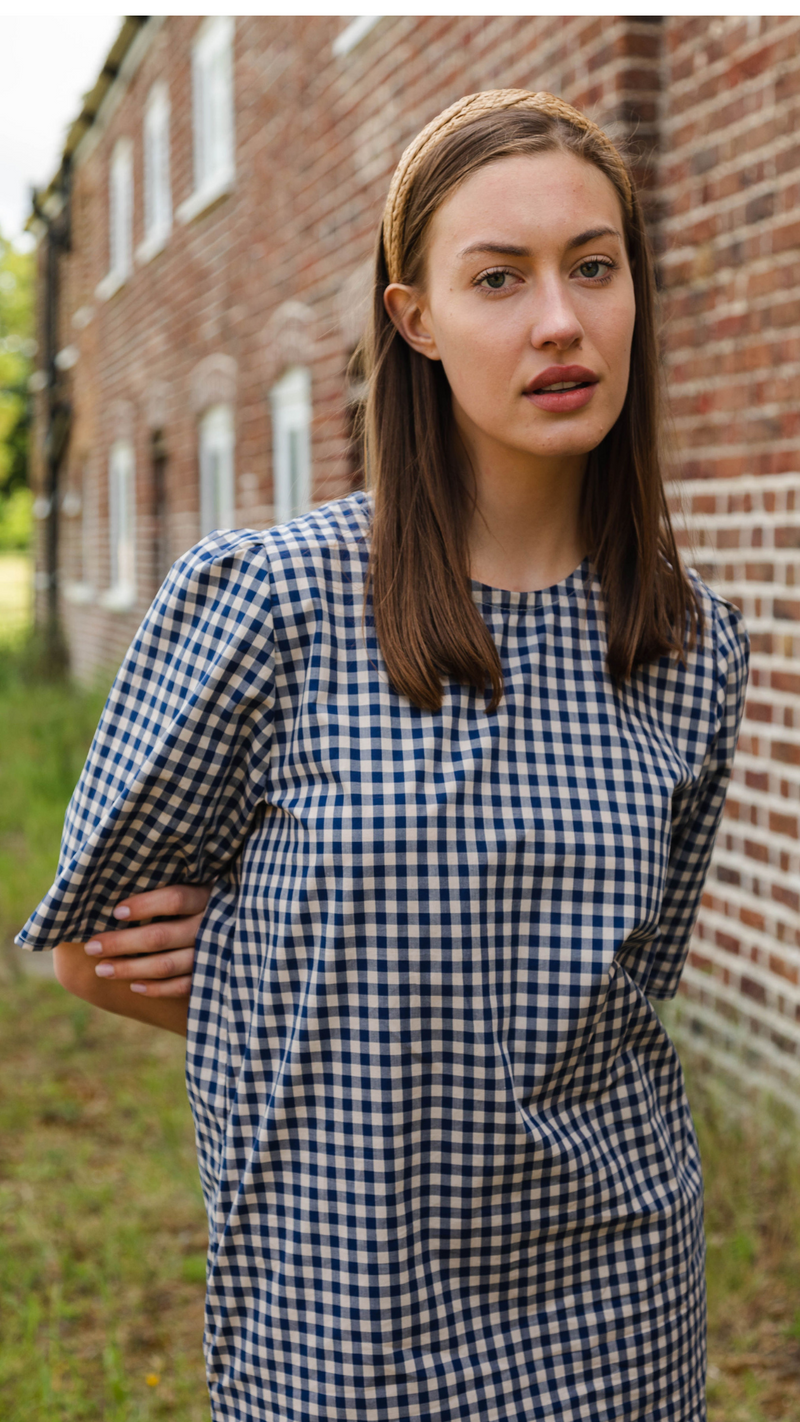 Comfortable cotton gingham check dress perfect for summer.  The Gunnera Dress by Kate Sheridan is an effortless and versatile wardrobe staple. Featuring puff sleeves, side pockets and a loop button fastening at the back.  100% cotton, made in the North of England by Kate Sheridan.