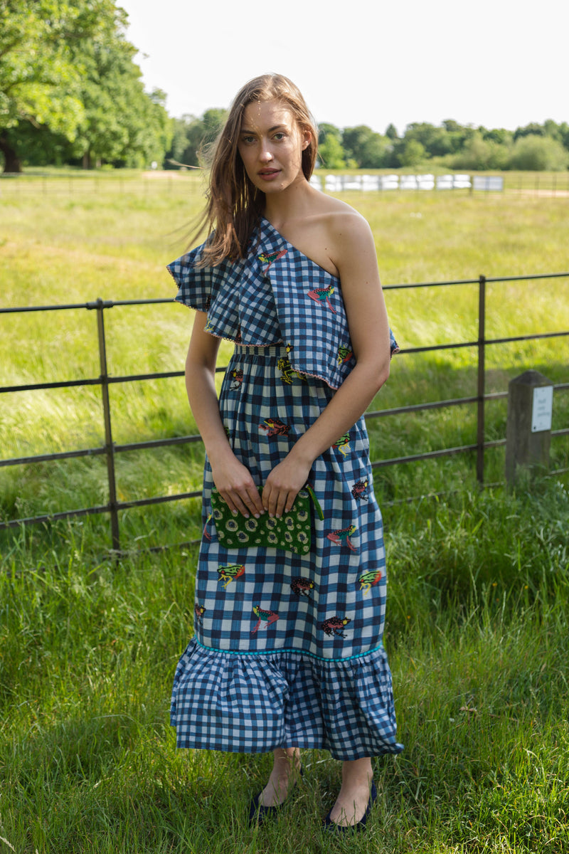 This cool blue gingham embroidered Moreena dress is by Conditions Apply. The dress is a classic one shoulder midi length in a crisp plaid print developed using light skin friendly cotton fabric that would be suitable for any day in the sun.  The beautifully embroidered frog motif adds a fun quirky twist to the statement dress