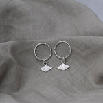 Textured shape earrings with a rhombus tag made out of recycled silver by April March Jewellery, sold by Percy Langley