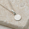 Textured shapes necklace with a round tag made out of recycled silver by April March Jewellery, sold by Percy Langley