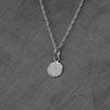 Textured shapes necklace with a round tag made out of recycled silver by April March Jewellery, sold by Percy Langley
