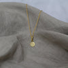 Textured shaped necklace with a round tag made out of fairmined gold vermeil by April March Jewellery, sold by Percy Langley